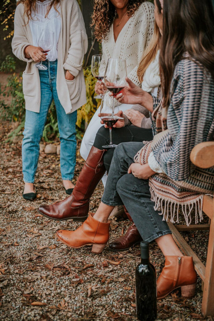 women holding glasses of wine in fall clothing