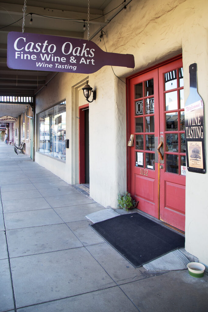 Sidewalk with a wine tasting shop with a purple sign and a red door