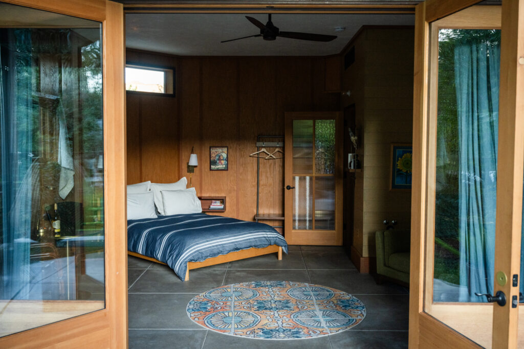 Doors and bedroom of a room at Boonville Hotel + Restaurant with blue drapes and blue striped duvet cover