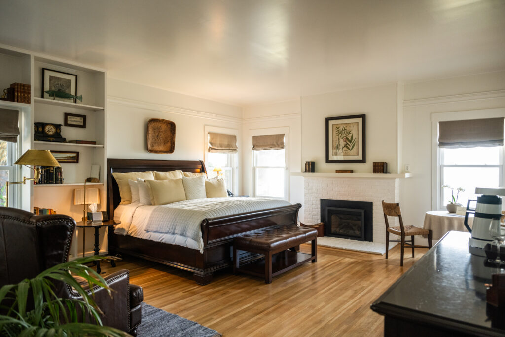 Room with large bed, various llamps, tables, and photos in main house at The Harbor House Inn, Restaurant, & Farm