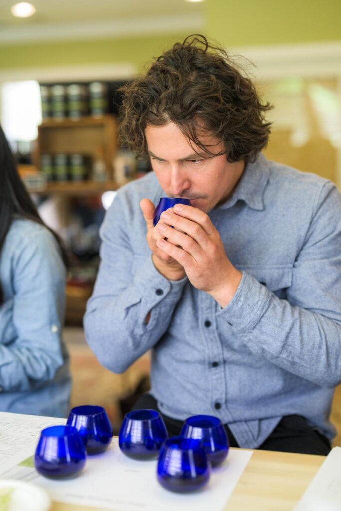 man smelling olive oil in blue glass