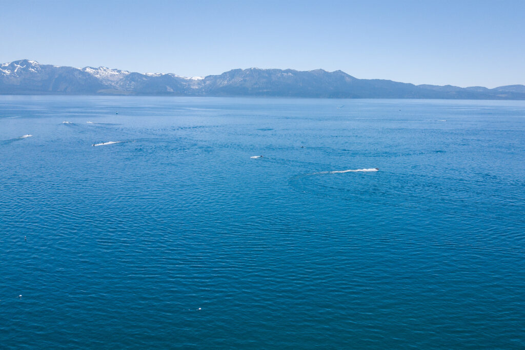 Aerial view of lake with boats and snow-capped mountains in the background