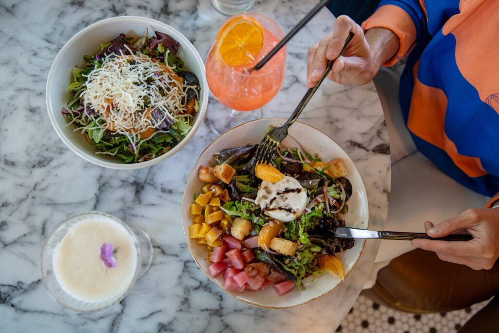 Photo of a salad with beets, burrata, greens, citrus, and croutons and a salad
