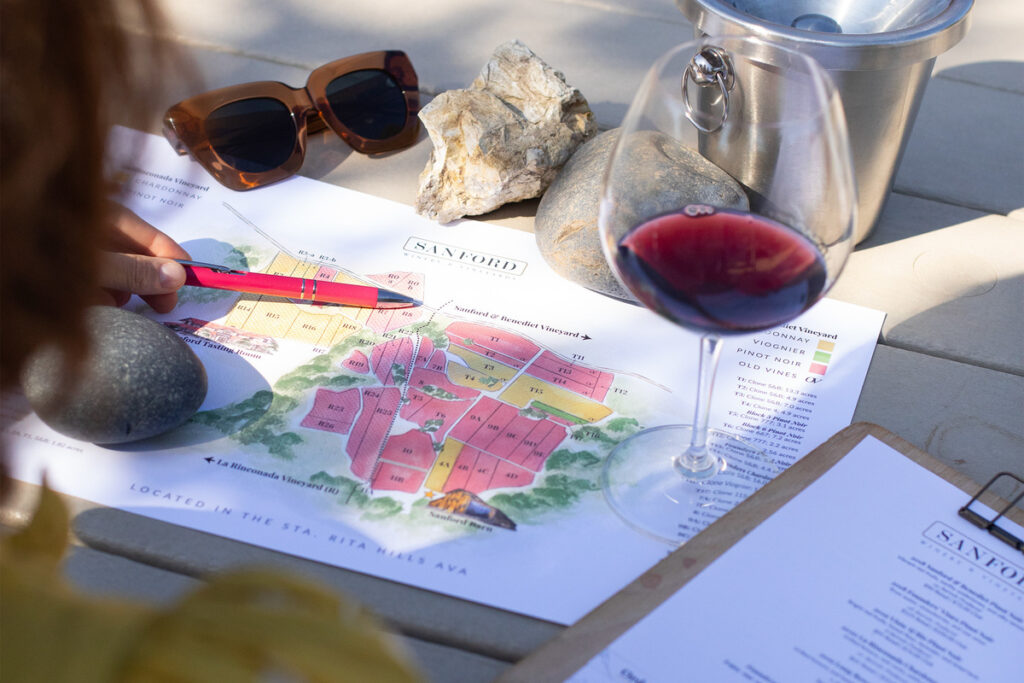 glass of red wine next to a map of sanford winery blocks at a ca central coast wineries