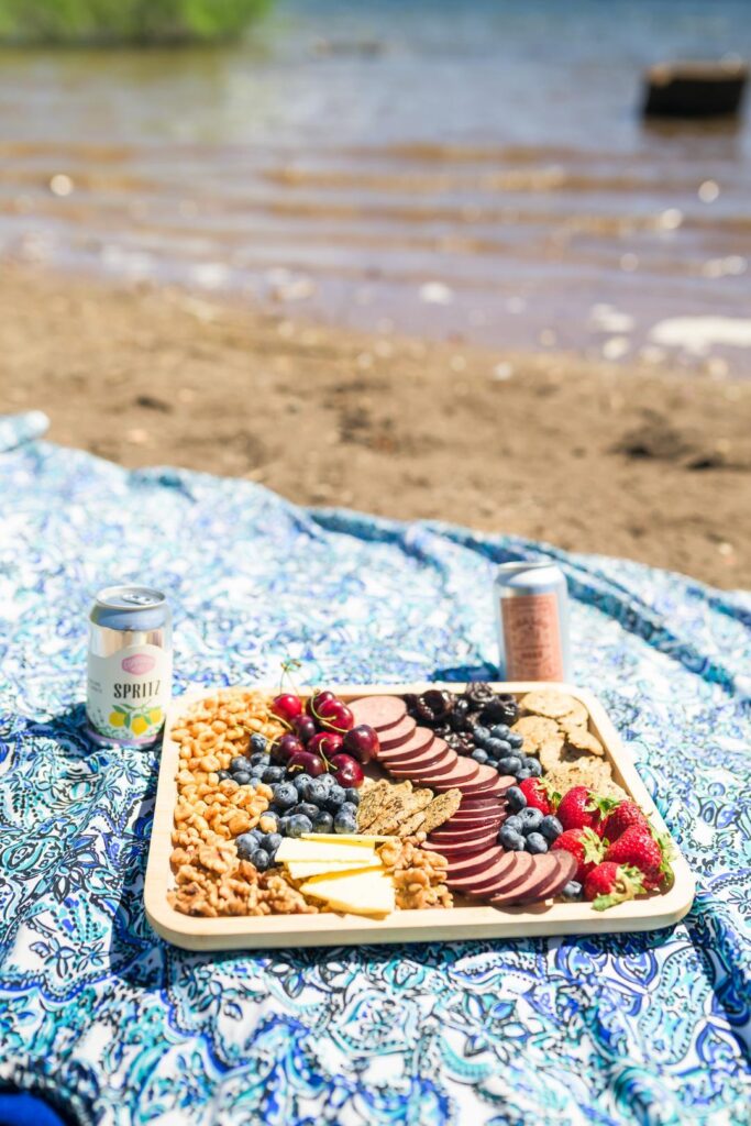 enjoying a charcuterie board and canned wine near a lake during a Northern California glamping trip 