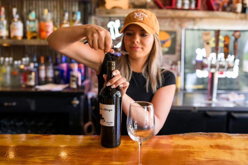 Bartender opening a bottle of wine at Five Marys Burgerhouse