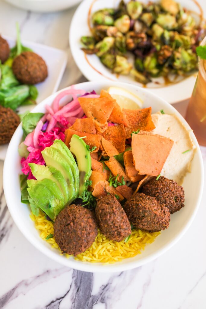 Photo of a falafel bowl with pita chips, avocado, hummus, and onions