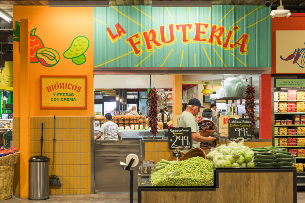 Photo of a fruit stand in a food hall with a person shopping 