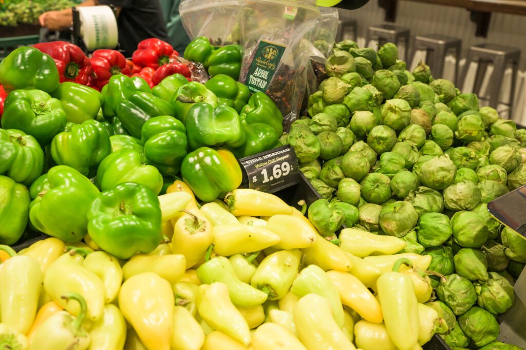 Close up shot of fresh produce used in Mexican cuisine like tomatillos, yellow chiles, and bell peppers